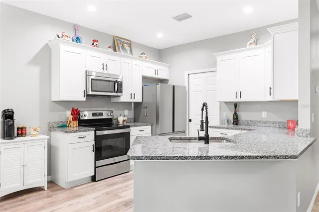 a kitchen with granite countertop a sink a stove and refrigerator
