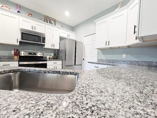 a kitchen with stainless steel appliances a sink a stove a microwave a refrigerator a window