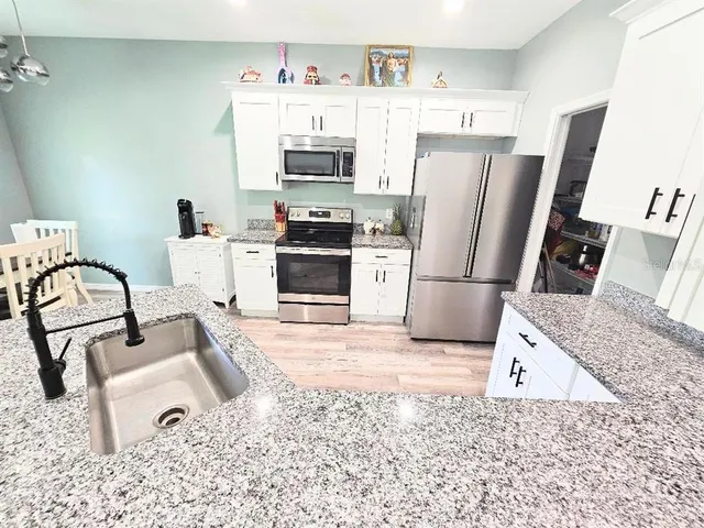 a kitchen with granite countertop a refrigerator stove and sink