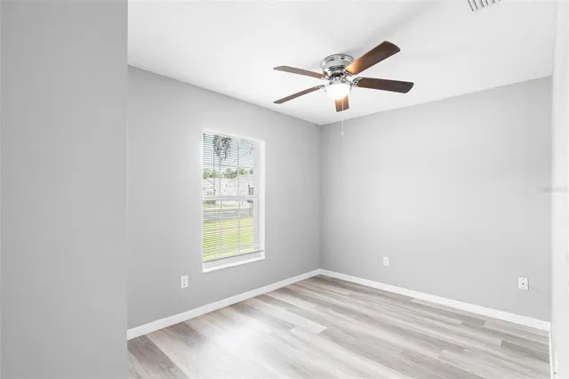 an empty room with windows and fan