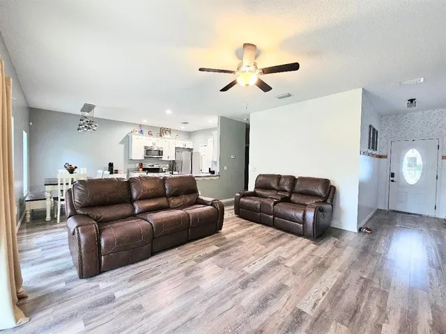 a living room with furniture a ceiling fan and a wooden floor