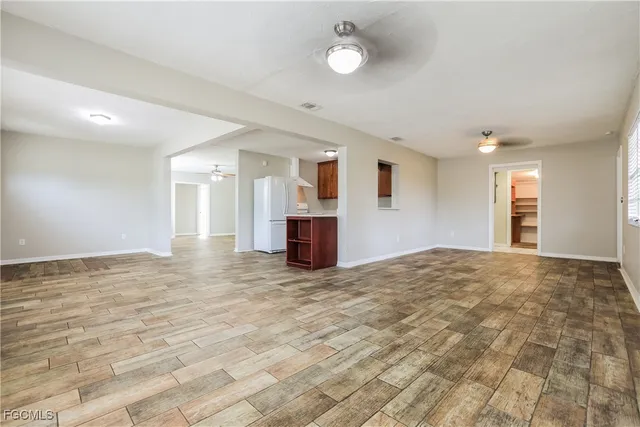 a view of empty room with kitchen and window