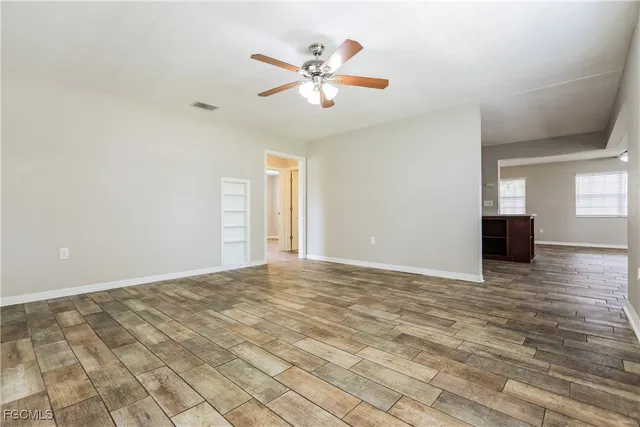 a view of an empty room with window and wooden floor