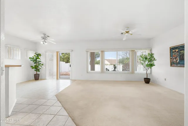 an empty room with windows and ceiling fan