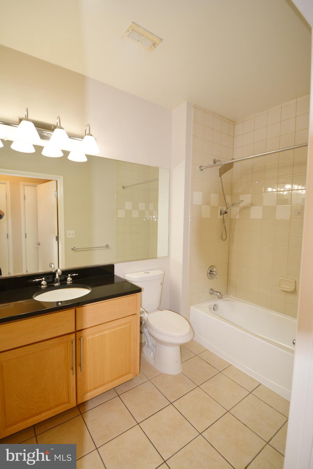1201 East W Highway, Unit 238 Silver Spring, MD 20910 - Photo 18 of 18 a bathroom with a granite countertop sink a toilet mirror and bathtub