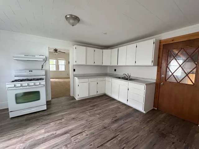 a kitchen with stainless steel appliances granite countertop a stove a sink and a refrigerator with wooden floors