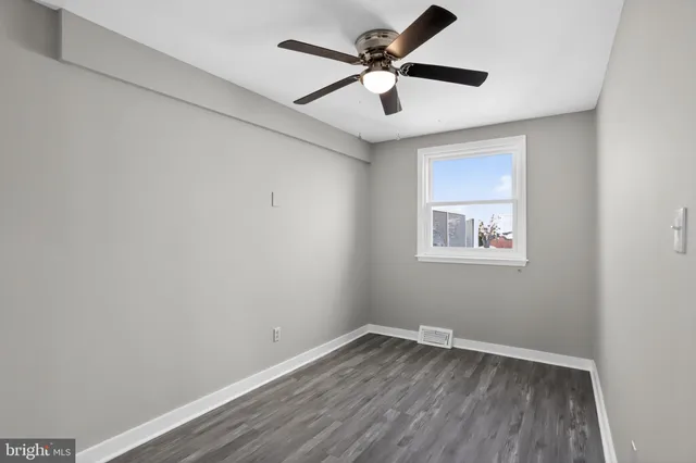 an empty room with wooden floor and ceiling fan