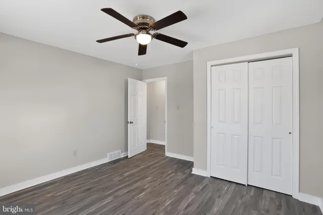 an empty room with wooden floor and ceiling fan