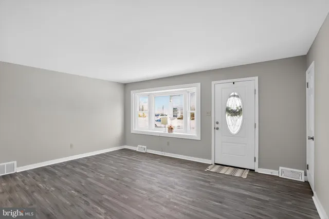 an empty room with wooden floor and window