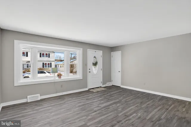 an empty room with wooden floor and window