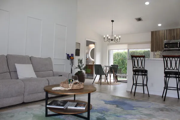 a living room with furniture kitchen view and a chandelier