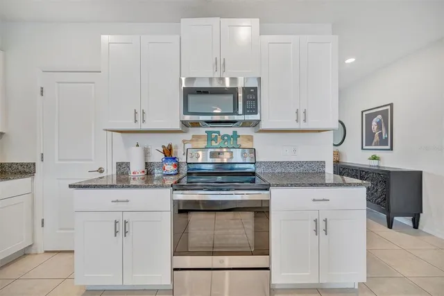 a kitchen with granite countertop a sink stove and refrigerator