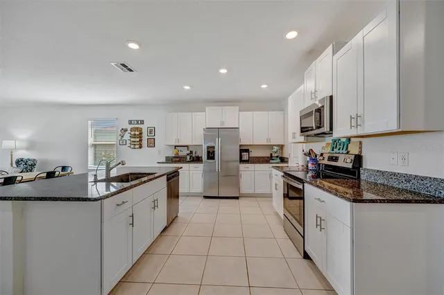 a large kitchen with stainless steel appliances granite countertop a sink and cabinets