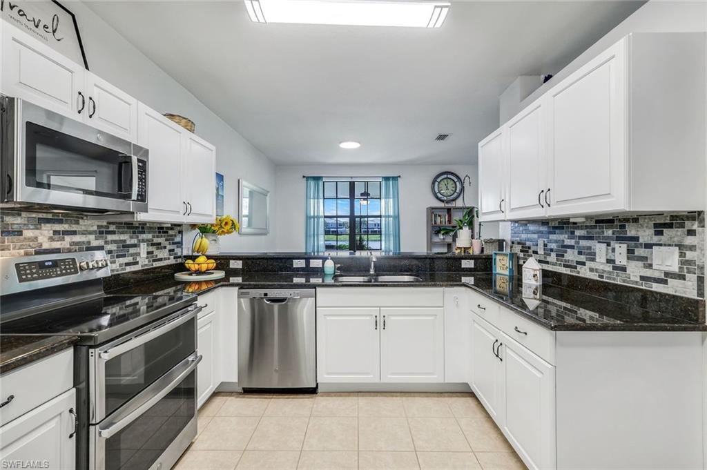 15239 Summit Pl Circle, Unit 246 Naples, FL 34119 - Photo 14 of 49 Kitchen with appliances with stainless steel finishes, decorative backsplash, dark stone countertops, light tile patterned floors, and recessed lighting