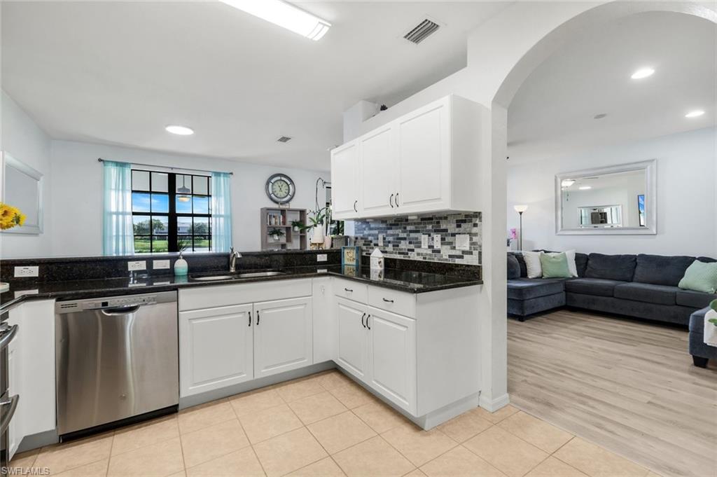 15239 Summit Pl Circle, Unit 246 Naples, FL 34119 - Photo 49 of 49 Kitchen with open floor plan, stainless steel dishwasher, light tile patterned floors, white cabinetry, and dark stone countertops