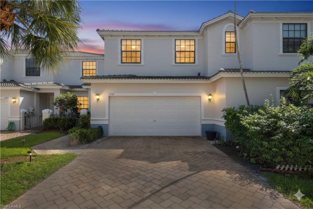 15239 Summit Pl Circle, Unit 246 Naples, FL 34119 - Photo 2 of 49 Mediterranean / spanish-style home featuring decorative driveway, an attached garage, a tile roof, and stucco siding