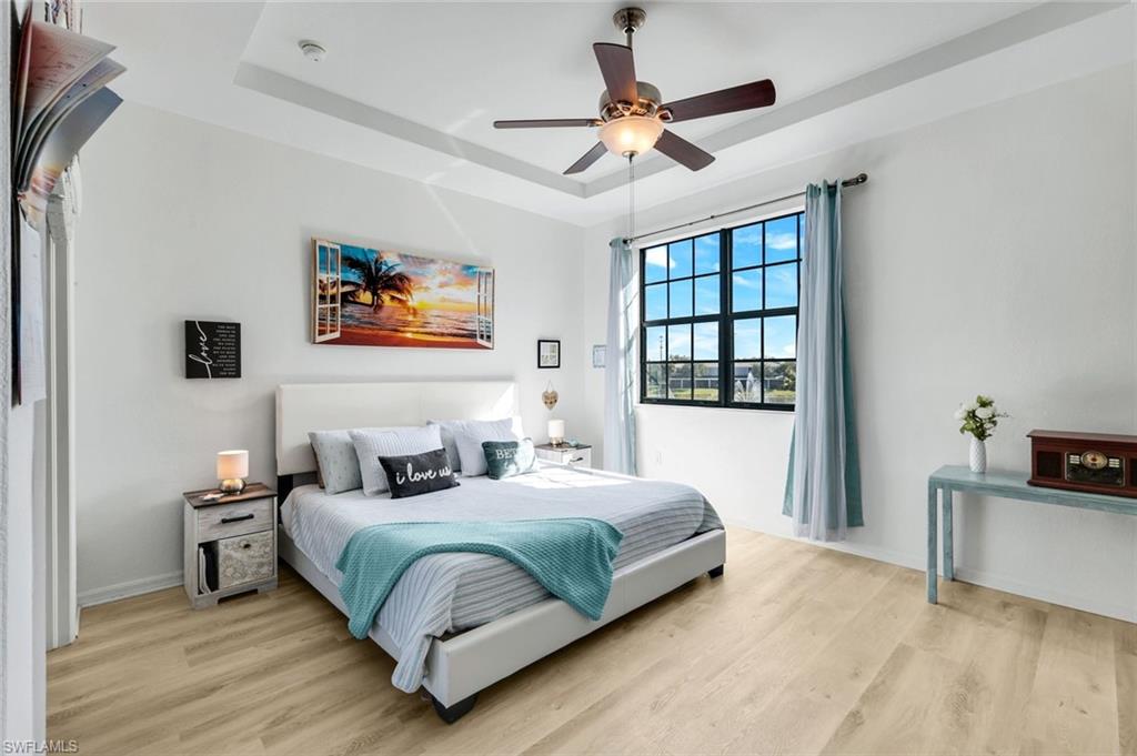 15239 Summit Pl Circle, Unit 246 Naples, FL 34119 - Photo 22 of 49 Bedroom with a tray ceiling, light wood-type flooring, and a ceiling fan