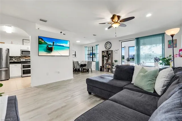 a living room with furniture kitchen view and a large window