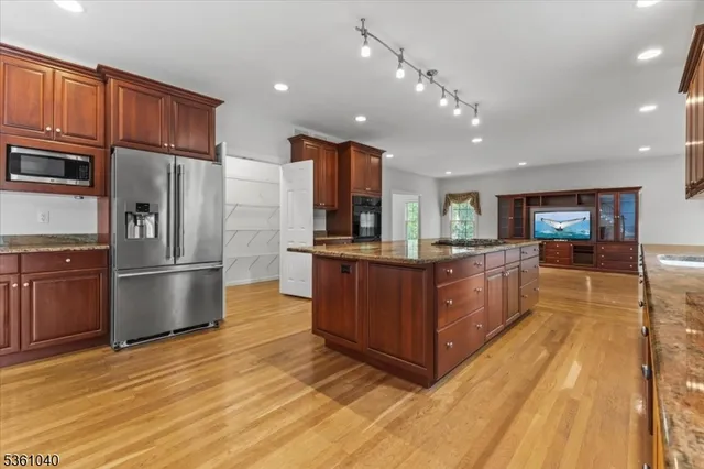 a kitchen with stainless steel appliances granite countertop wooden cabinets a sink and dishwasher a stove with wooden floor