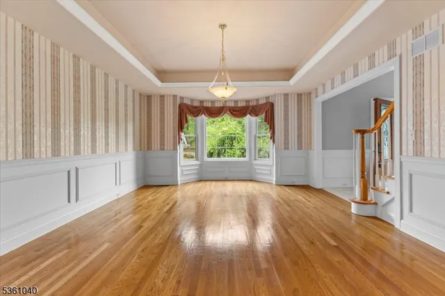 a view of a kitchen with an empty room and wooden floor