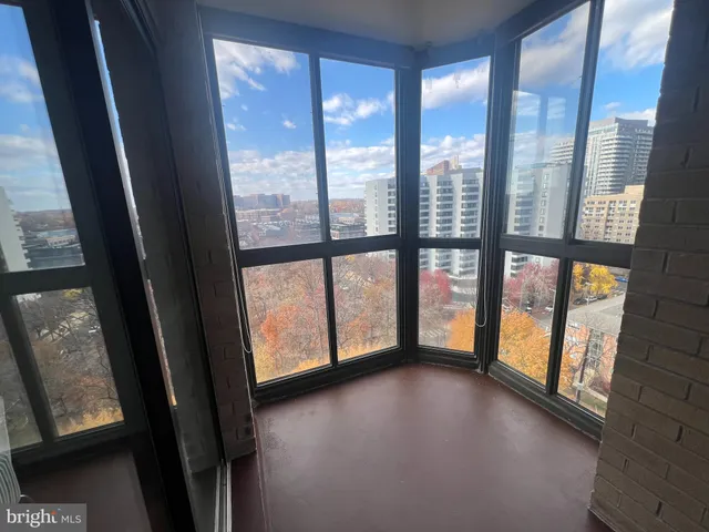 a view of an empty room with large windows and a small yard