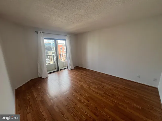 a view of an empty room with wooden floor and window