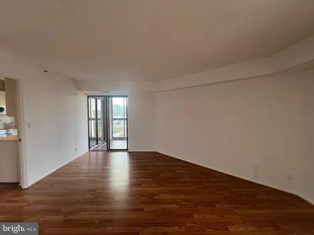 a view of an empty room with window and wooden floor