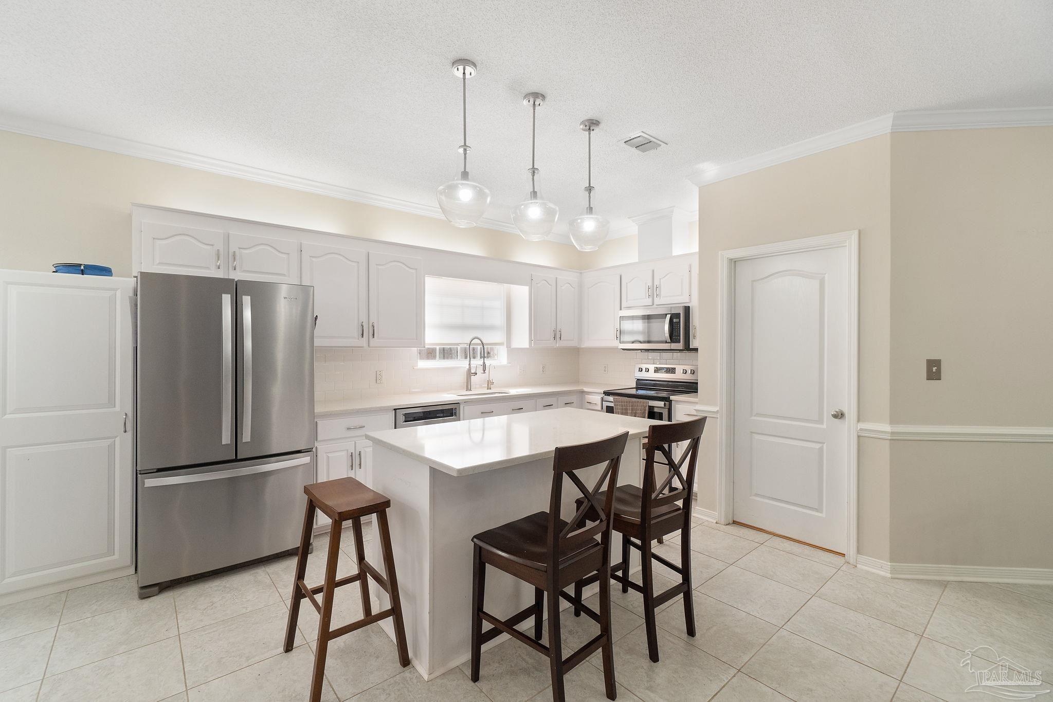 1504 Muirfield Road Cantonment, FL 32533 - Photo 13 of 35 a kitchen with kitchen island a appliances a counter space and a refrigerator