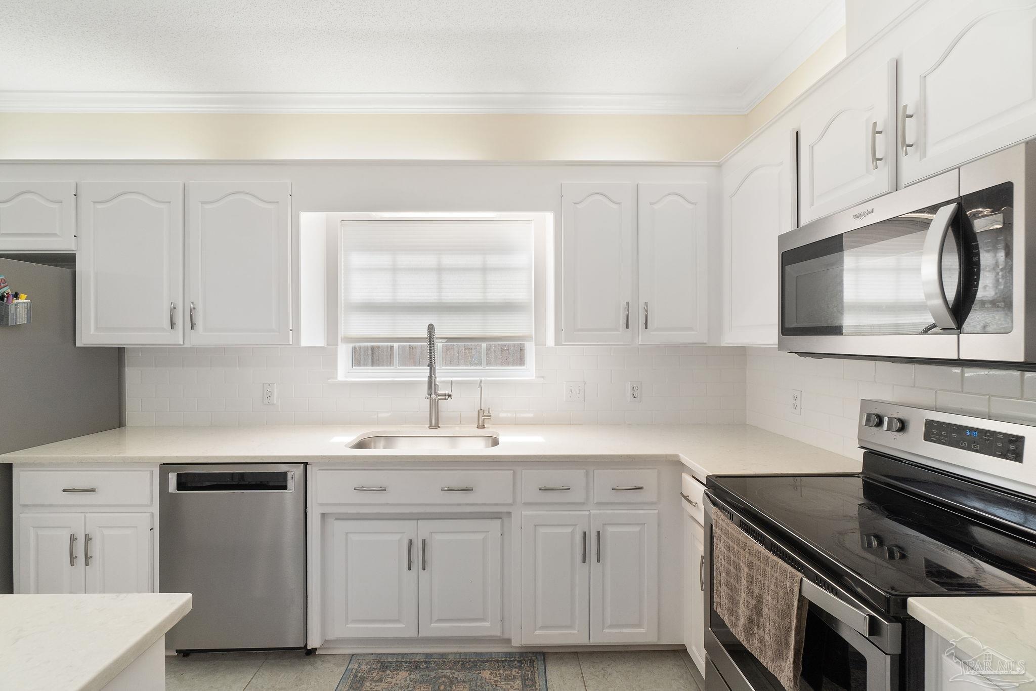 1504 Muirfield Road Cantonment, FL 32533 - Photo 15 of 35 a kitchen with stainless steel appliances white cabinets and a sink