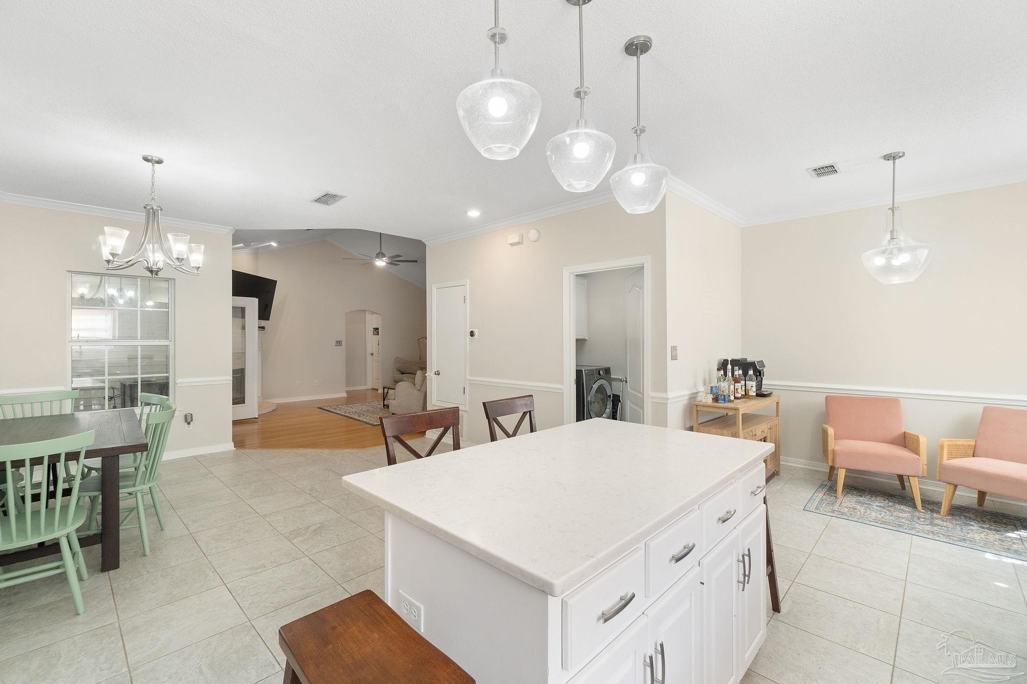 1504 Muirfield Road Cantonment, FL 32533 - Photo 10 of 35 a large white kitchen with a large island oven a stove and a dining table with garden view