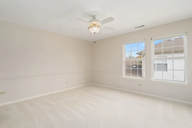 an empty room with a ceiling fan and window