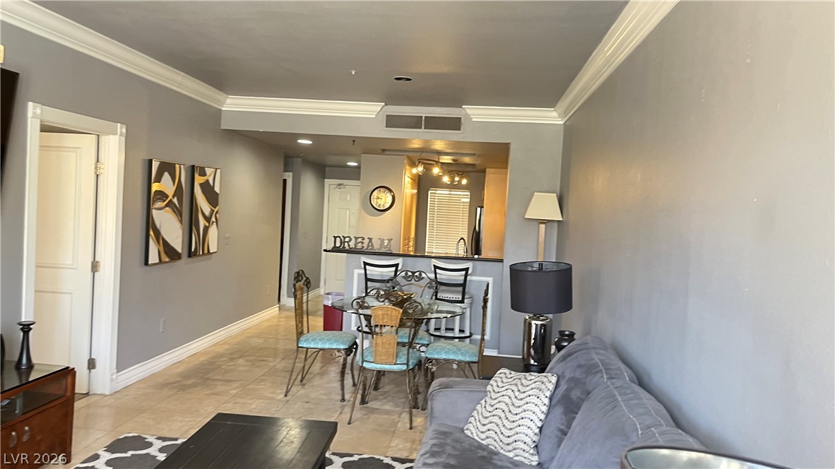 210 East Flamingo Road, Unit 205 Las Vegas, NV 89169 - Photo 6 of 17 Elegant crown molding adorns the living area, featuring an open plan with a kitchen pass-through and a breakfast bar.