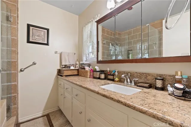 a bathroom with a granite countertop sink and a mirror