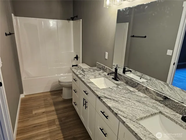a bathroom with a granite countertop sink a toilet and shower
