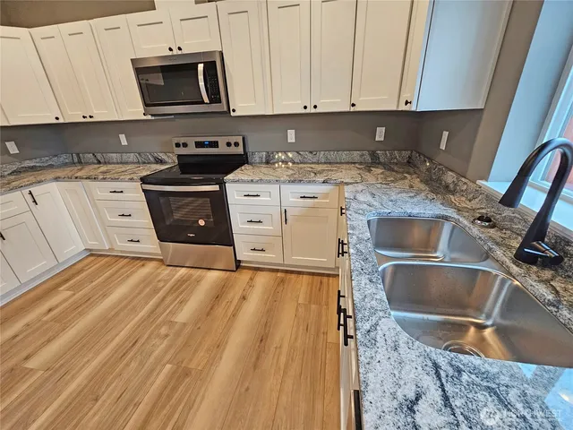a kitchen with stainless steel appliances granite countertop a sink stove and cabinets