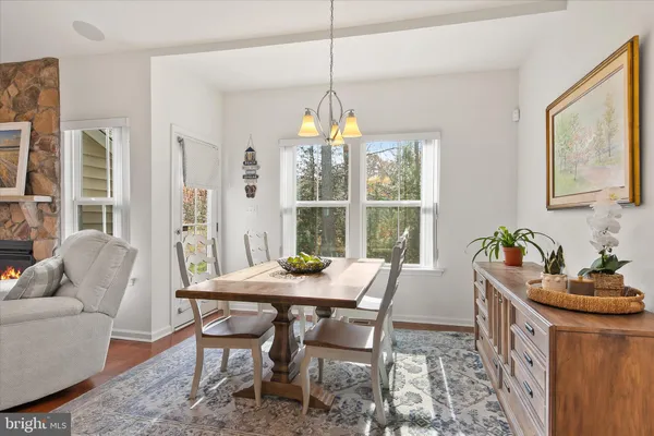 a view of a dining room and livingroom with furniture wooden floor a rug a fireplace and a chandelier