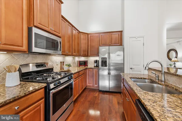 a kitchen with stainless steel appliances granite countertop a stove top oven a sink dishwasher a dining table and chairs with wooden floor