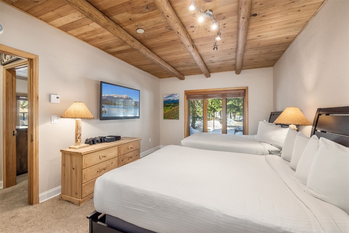 1203 West Keystone Road, Unit 2709 Keystone, CO 80435 - Photo 25 of 48 Bedroom featuring baseboards, wood ceiling, access to exterior, light colored carpet, and vaulted ceiling with beams