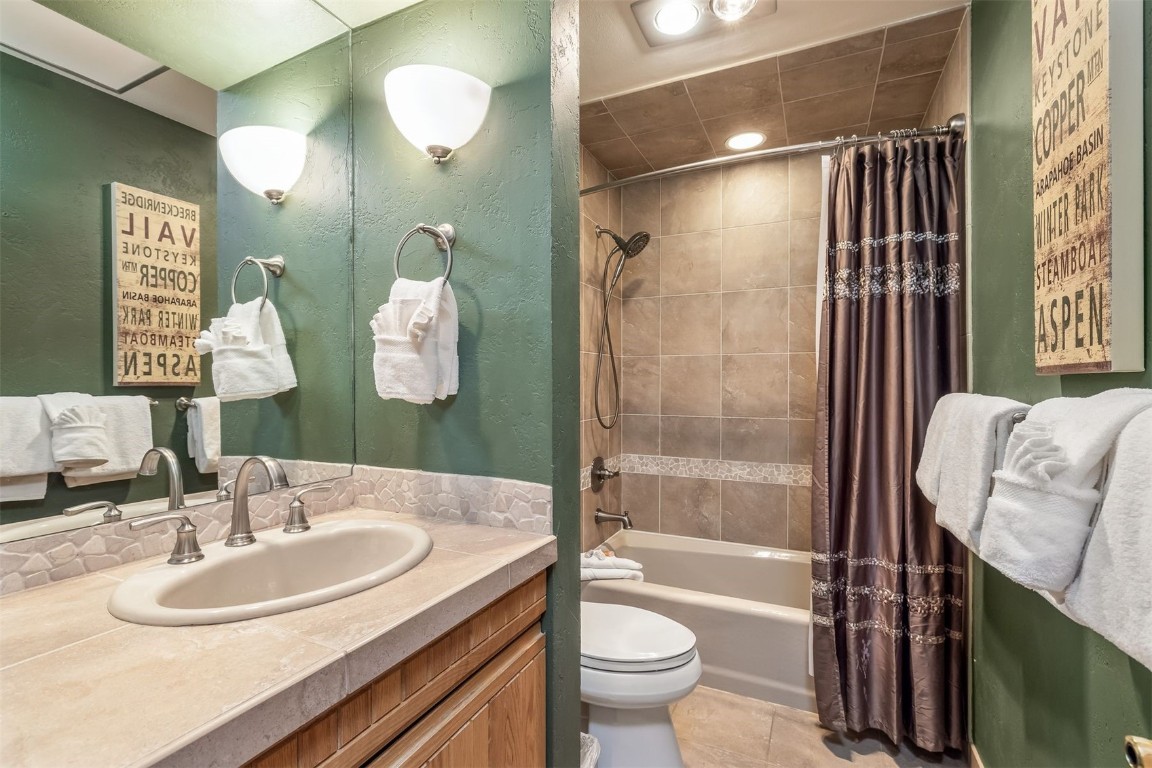 1203 West Keystone Road, Unit 2709 Keystone, CO 80435 - Photo 30 of 48 Bathroom featuring toilet, a textured wall, shower / bathtub combination with curtain, vanity, and tile patterned flooring