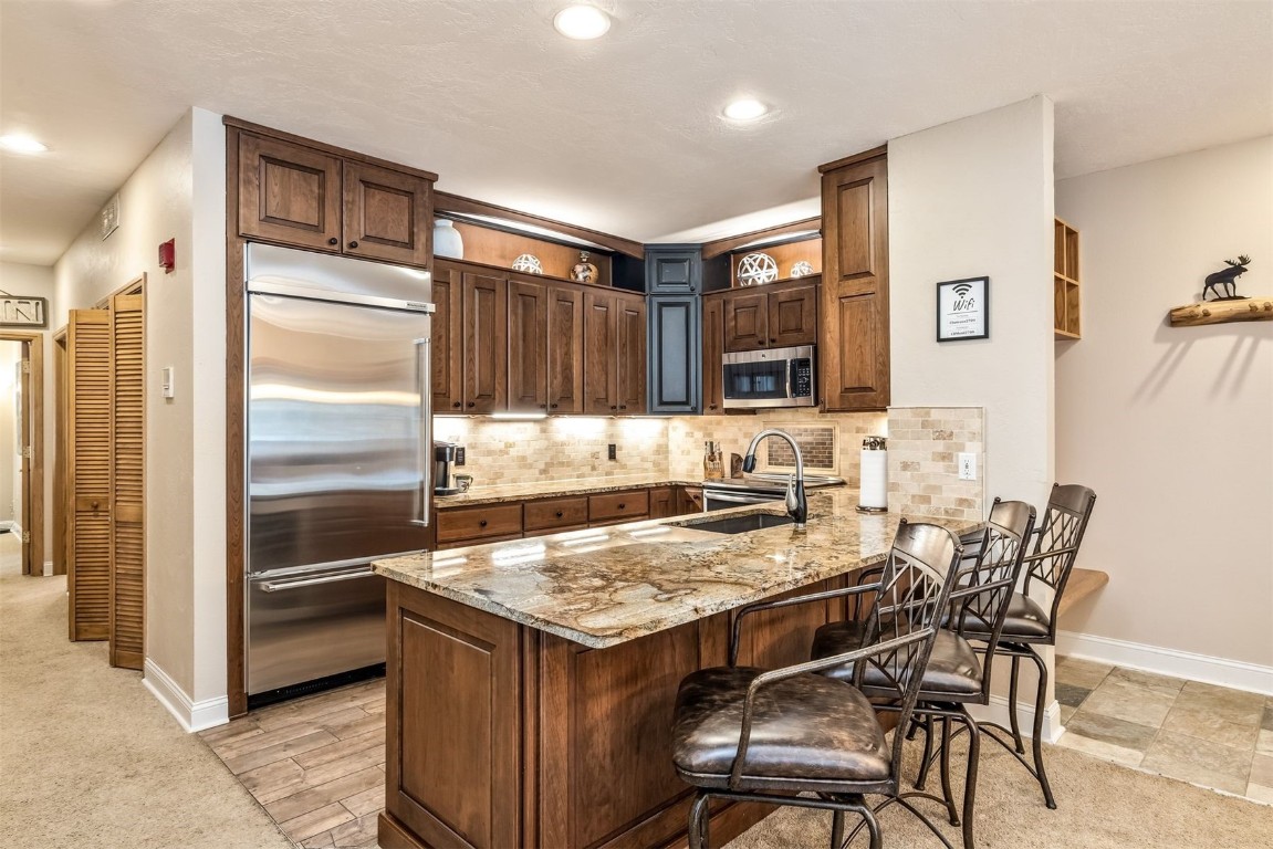 Kitchen featuring stainless steel appliances, a peninsula, a sink, and decorative backsplash