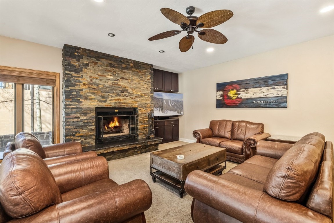 Living room featuring ceiling fan, recessed lighting, light colored carpet, and a fireplace
