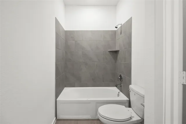 a bathroom with a toilet and white tub
