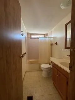 a bathroom with a granite countertop bathtub shower sink vanity and toilet