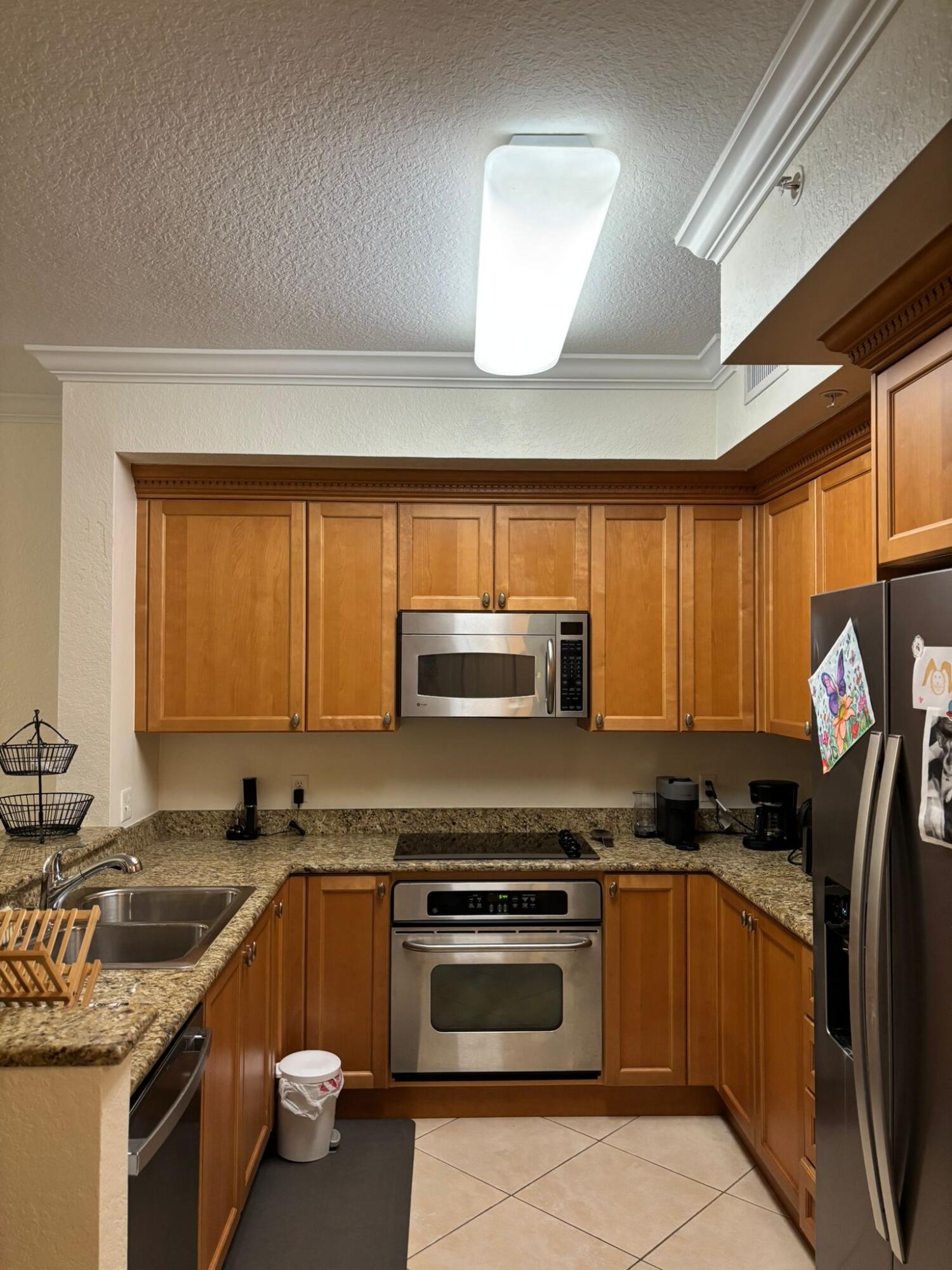 4112 Renaissance Way, Unit 112 Boynton Beach, FL 33426 - Photo 1 of 10 a kitchen with stainless steel appliances granite countertop a stove a sink and a microwave