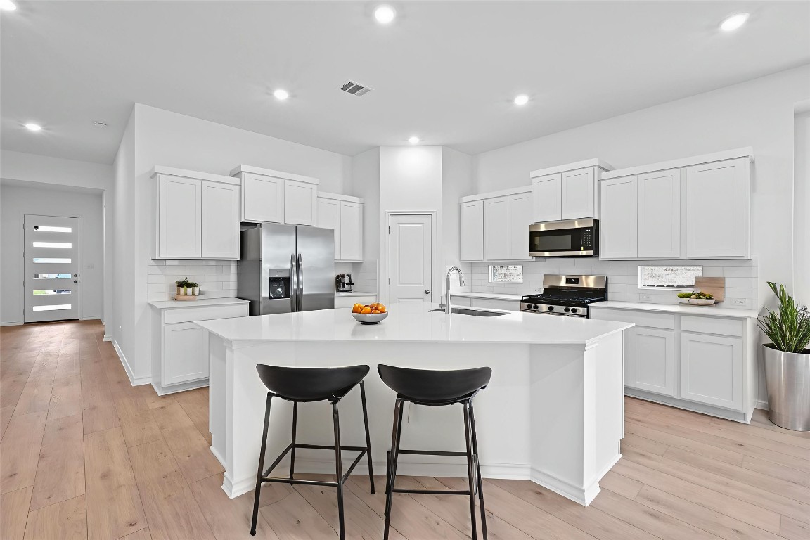 1617 Dove Rnch Road Georgetown, TX 78628 - Photo 8 of 25 a kitchen with stainless steel appliances a stove a sink a refrigerator white cabinets and wooden floor