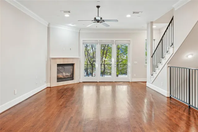 a view of an empty room with wooden floor fireplace and a window
