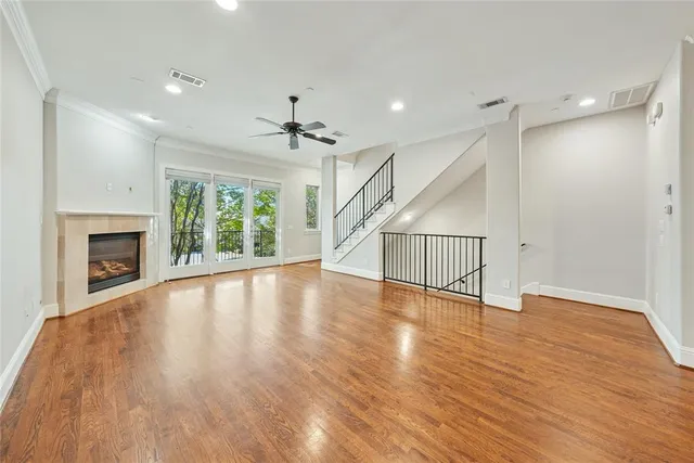 a view of an empty room with wooden floor fireplace and a window