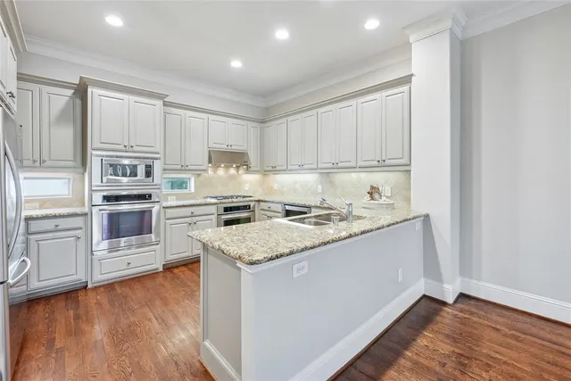 a kitchen with stainless steel appliances granite countertop a stove top oven a sink and a refrigerator