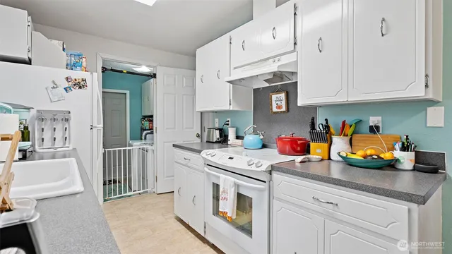 a kitchen with stainless steel appliances granite countertop a stove a sink dishwasher and white cabinets