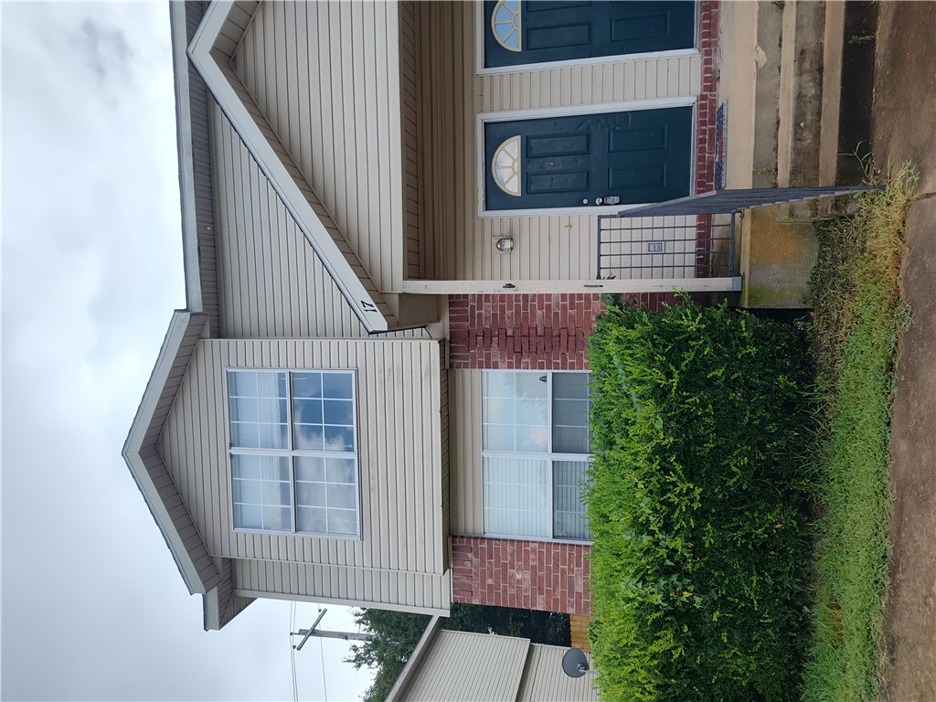 17 West Rainsong Street Farmington, AR 72730 - Photo 1 of 13 Two-story multi-unit dwelling featuring a brick and siding exterior, multiple entry doors with arched transom windows, and a raised concrete porch with metal railings